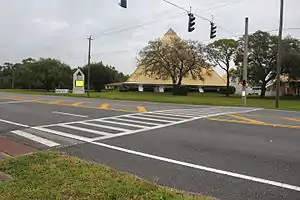 An image of a marked pedestrian crossing in the "ladder" style with a lighted pedestrian stop signal (red hand).
